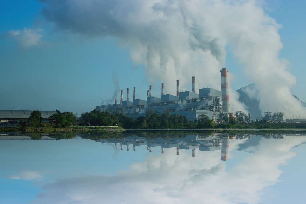 Image of a coal fired power plant by a body of water. Canva image.