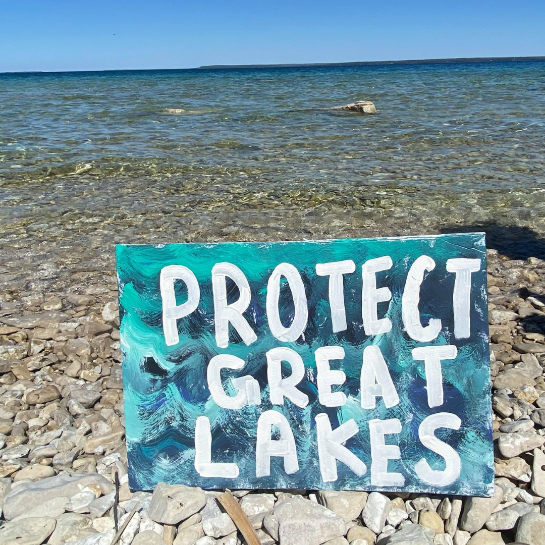 Sign on rocky shoreline of Mackinac Straits: "Protect Great Lakes"