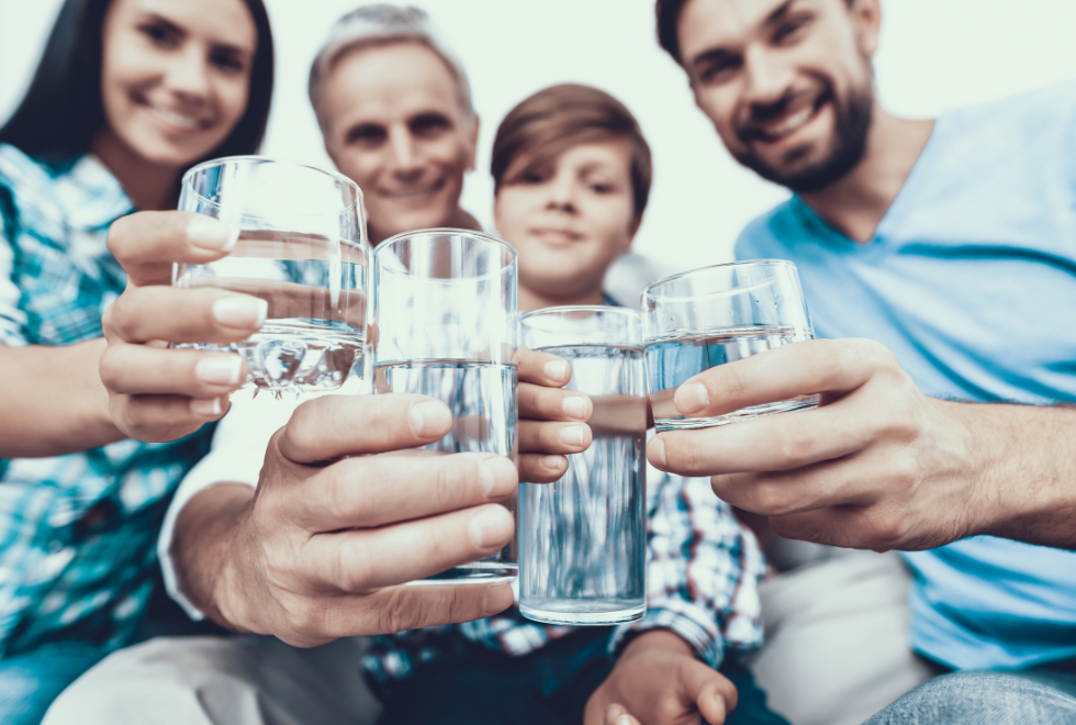 Four people holdiing glasses of water stretching their arms out