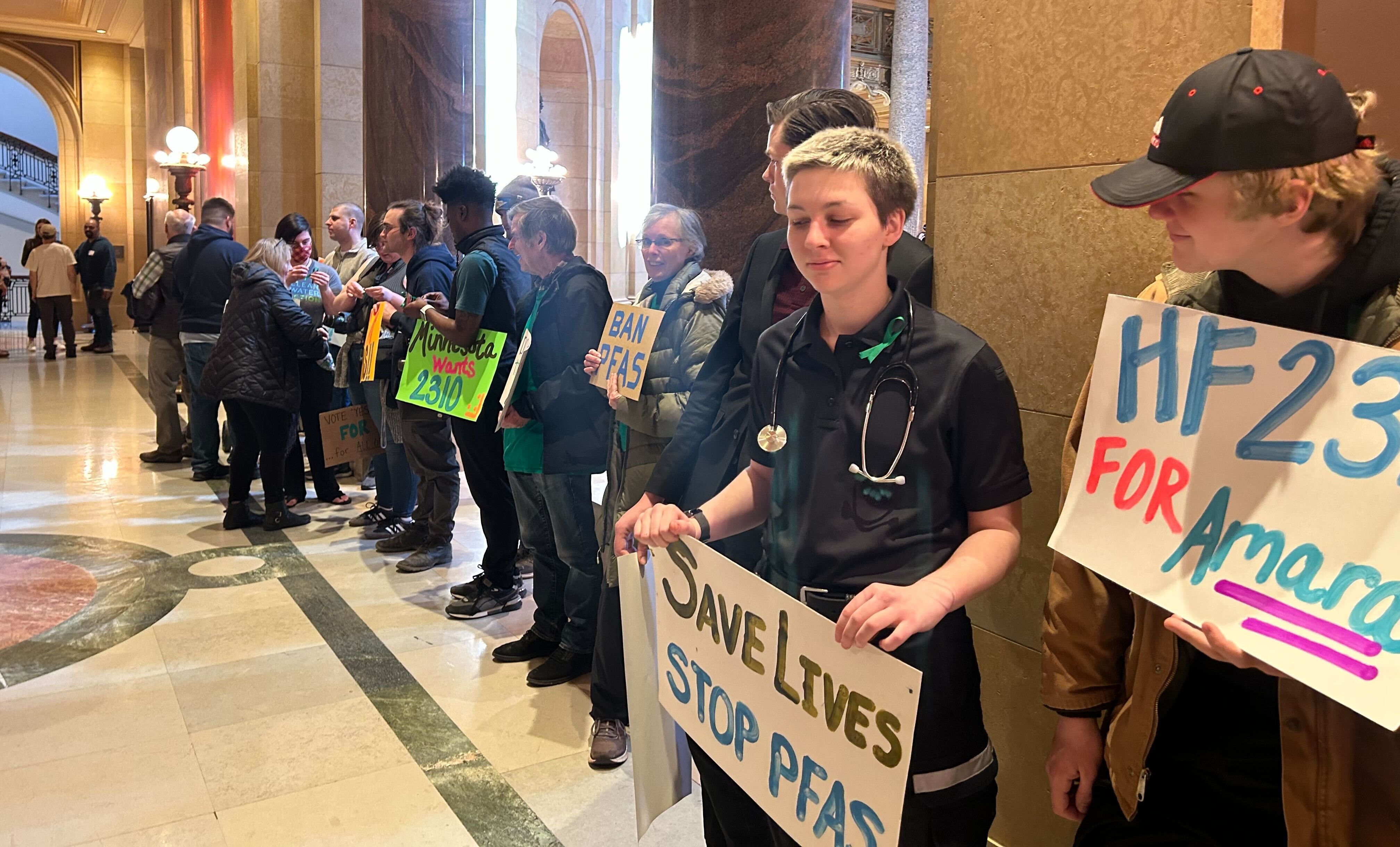 Rally in the Capitol building with signs like "Save Lives - Stop PFAS"