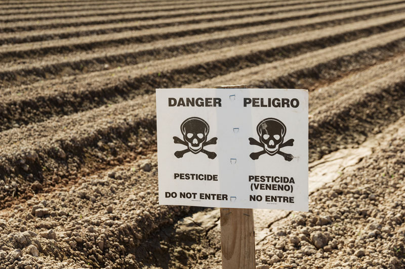 Farm field with a pesticide warning sign. Photo credit: Tom Grundy / Shutterstock