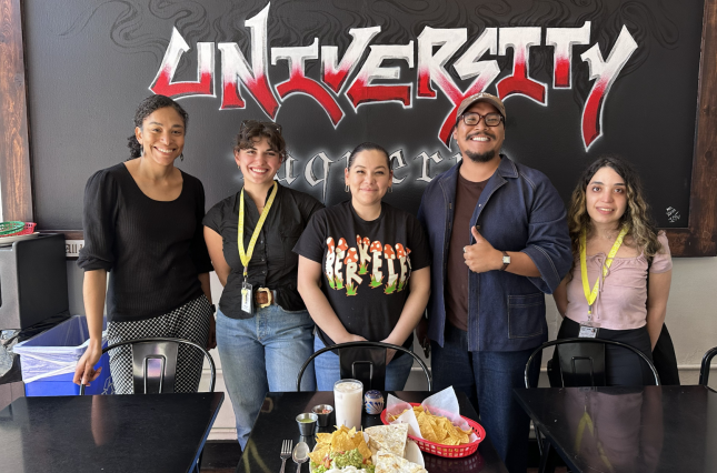 Five staff members from University Taqueria showing off a dine-in table setting with reusable cups and utensils