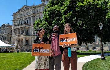 Michigan staff holding Taking Back Out Power signs in front of the State Capitol 