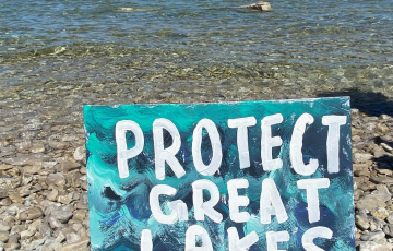 Sign on rocky shoreline of Mackinac Straits: "Protect Great Lakes"