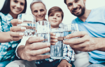 Four people holdiing glasses of water stretching their arms out