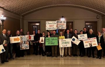 A dozen people stand together at a rally in the Minnesota Capitol building holding handmade signs such as "Amara's Law Protects Us All"