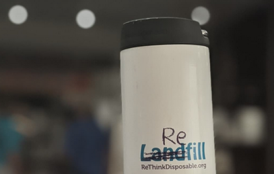 Reusable coffee mug with scribble over the word "Landfill" to read "Refill". Rethinkdisposable.org