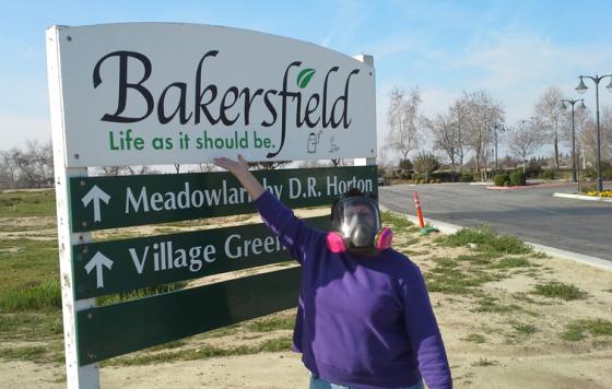 Rosanna in a respirator in front of a Bakersfield's sign